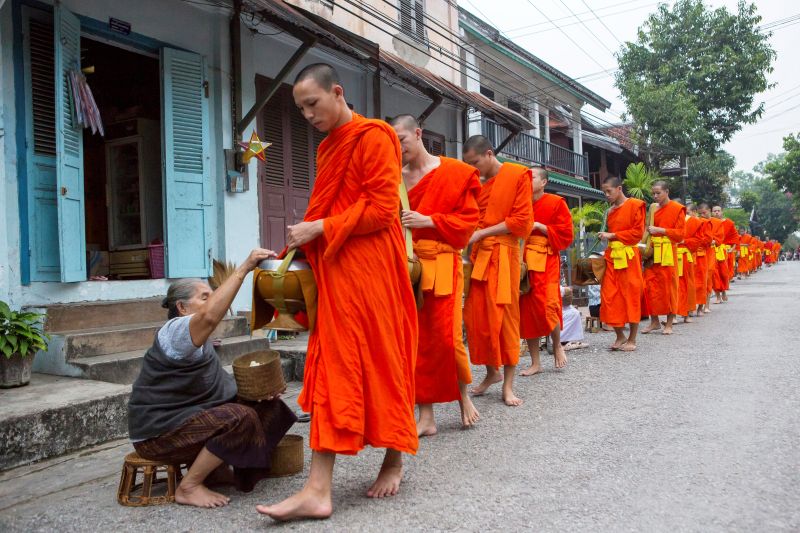 a-woman-offers-alms-to-a-procession-of-buddhist-mo-2026-01-09-10-44-00-utc